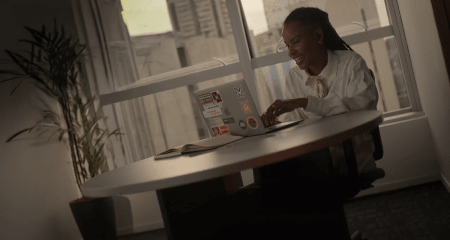 Mujer sonriendo mientras escribe en un portátil